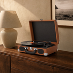 Platine vinyle Escale cognac ouverte sur un buffet en noyer, à côté d'une lampe